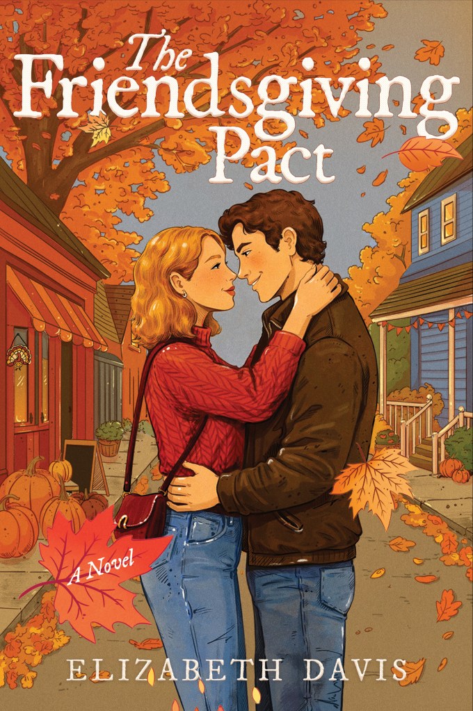 A white couple (her blonde in a red sweater, him brunette in a leather jacket) holding onto each other (her his shoulders, him her waist) in an autumnal small town street